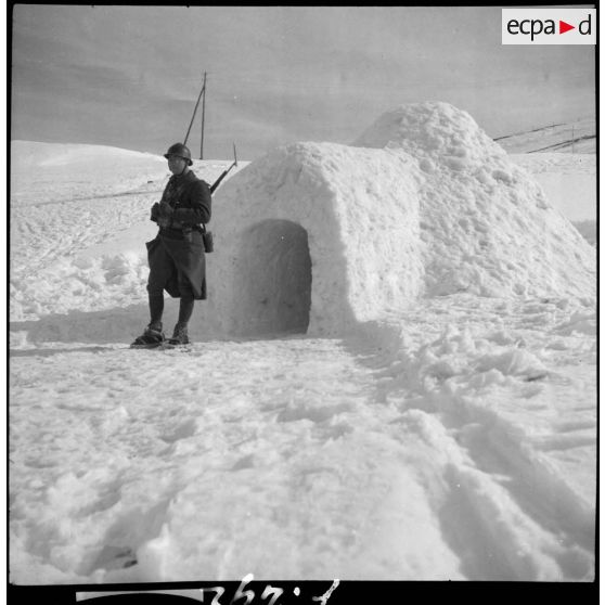 Un chasseur alpin de la 6e armée est en faction devant un igloo.