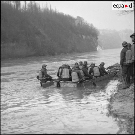 Des sapeurs du génie de la 6e armée manoeuvrent à la pagaie une barge pour la construction d'un pont flottant.
