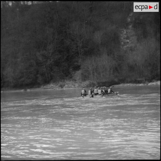 Des sapeurs du génie de la 6e armée manoeuvrent à la pagaie une barge pour la construction d'un pont flottant.