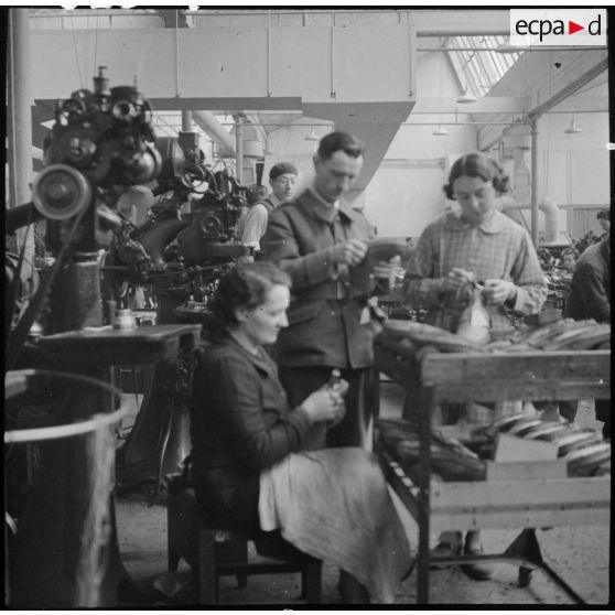 Des ouvrières et des soldats travaillent à la fabrication de chaussures pour l'armée dans une usine.