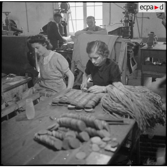 Des ouvrières et des soldats travaillent à la fabrication de chaussures pour l'armée dans une usine.
