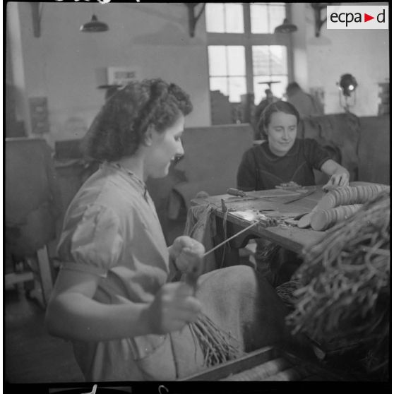 Des ouvrières et des soldats travaillent à la fabrication de chaussures pour l'armée dans une usine.