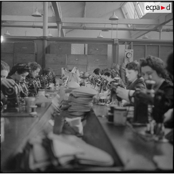 Des ouvrières et des soldats travaillent à la fabrication de chaussures pour l'armée dans une usine.
