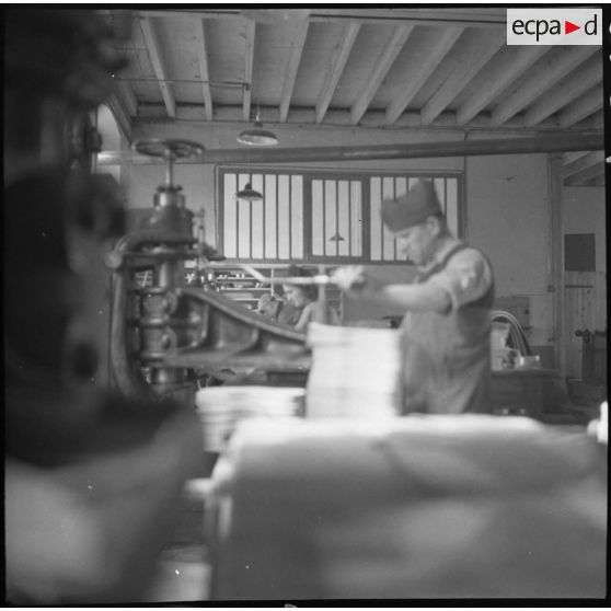 Des ouvrières et des soldats travaillent à la fabrication de chaussures pour l'armée dans une usine.