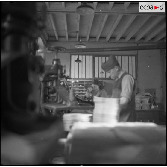 Des ouvrières et des soldats travaillent à la fabrication de chaussures pour l'armée dans une usine.