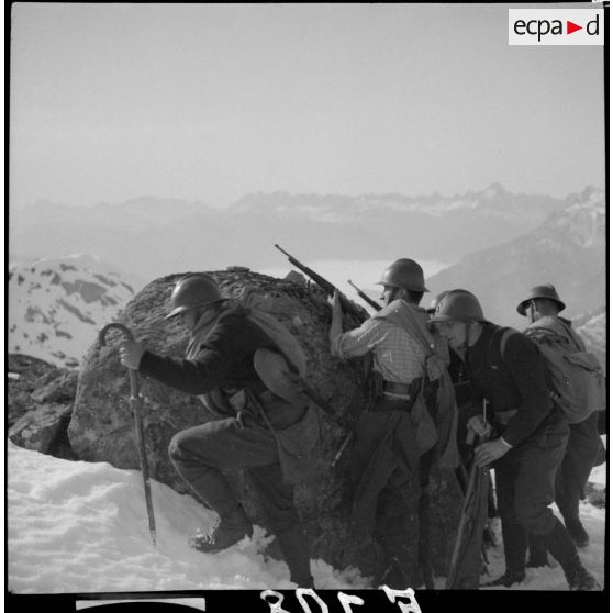 Des éclaireurs du 86e BCA sont postés dans la neige derrière un rocher.