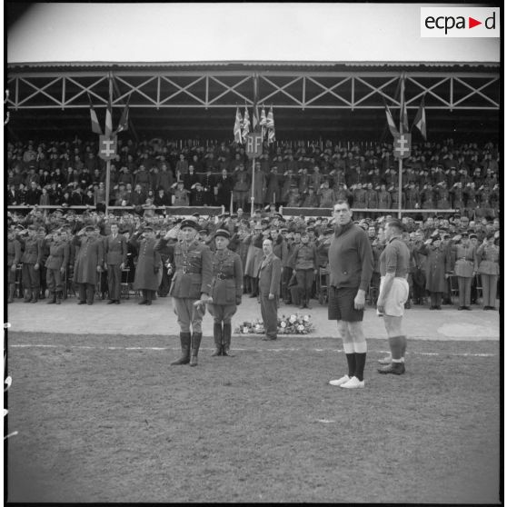De nombreux soldats et officiers font le salut militaire à l'occasion d'une rencontre sportive entre la France et la Grande-Bretagne.