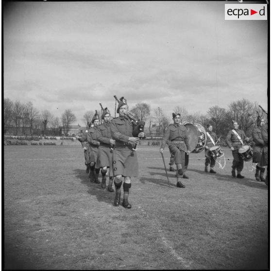 Un orchestre de la British expeditionary force défile sur un terrain de rugby.