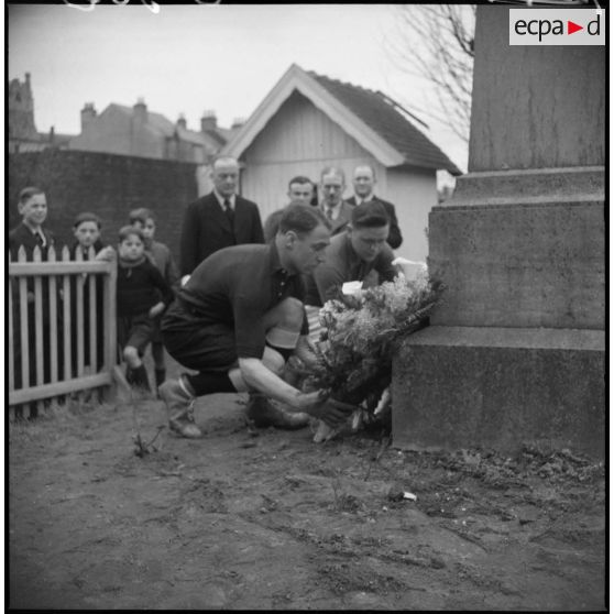Deux rugbymen français et britannique déposent une gerbe de fleur au pied d'un monument aux morts.