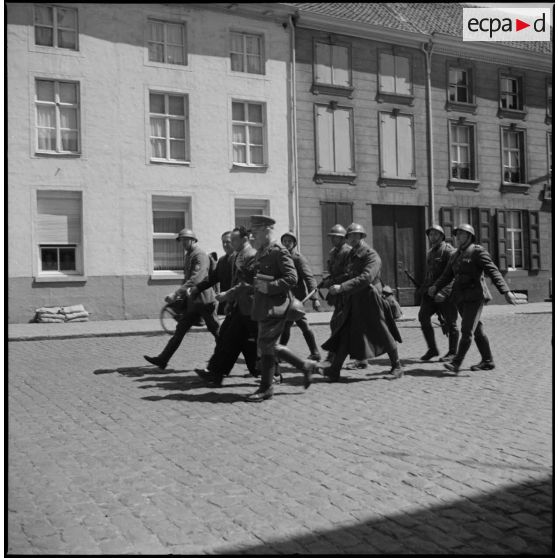 Des soldats et un officier belge dans une rue.
