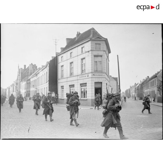 Des soldats français traversent une rue dans une ville belge.