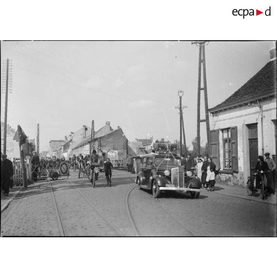 Des civils belges traversent une voie ferrée dans un village belge durant l'exode de mai 1940.