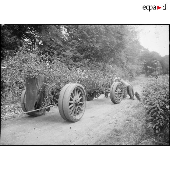 Des soldats de la 7e armée s'affairent autour d'un canon long Schneider de calibre 220 mm (modèle 1917) sur une route de campagne.
