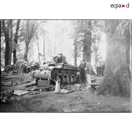 Des mécaniciens réparent un char français Renault R35 entreposé dans un bois à l'arrière du front.