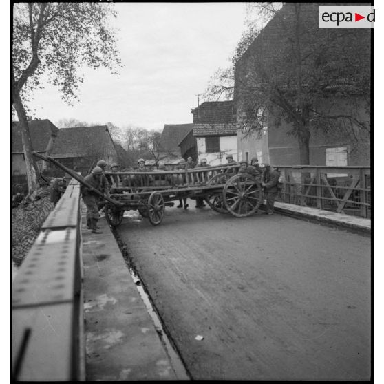 Des motocyclistes d'une unité de cavalerie amènagent une barricade à l'aide d'une charette.