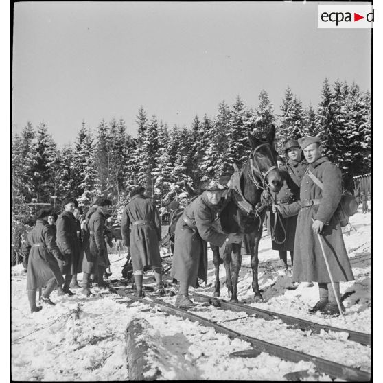 Des chasseurs alpins du 96e RIA tirent un chariot sur une voie de Decauville enneigée.