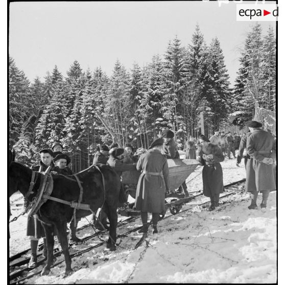 Des chasseurs alpins du 96e RIA tirent un chariot sur une voie de Decauville enneigée.