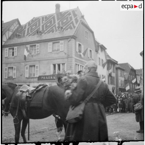 Un officier de la 8e armée s'apprête à remettre un bouquet de fleurs à des habitants de Ribeauvillé.