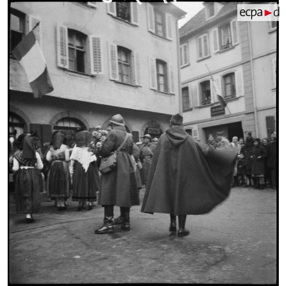 Soldats de la 8e armée, dont un commandant et deux lieutenants, offrant des fleurs aux habitantes de Ribeauvillé au cours d'une fête traditionnelle.