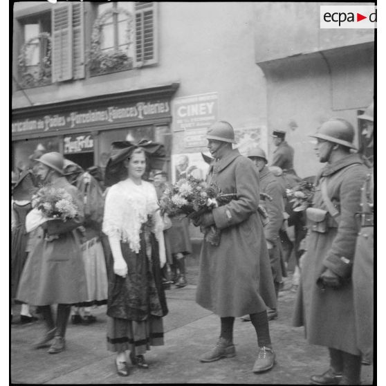 Soldats de la 8e armée, dont un commandant et deux lieutenants, offrant des fleurs aux habitantes de Ribeauvillé au cours d'une fête traditionnelle.