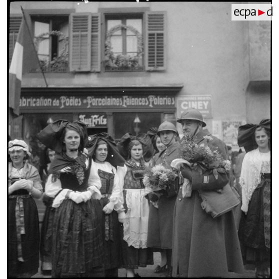 Soldats de la 8e armée, dont un commandant et deux lieutenants, offrant des fleurs aux habitantes de Ribeauvillé au cours d'une fête traditionnelle.