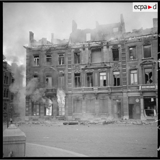 Bâtiments de la place Leopold de Namur en ruines et en feu après les bombardements allemands du 12 mai 1940.