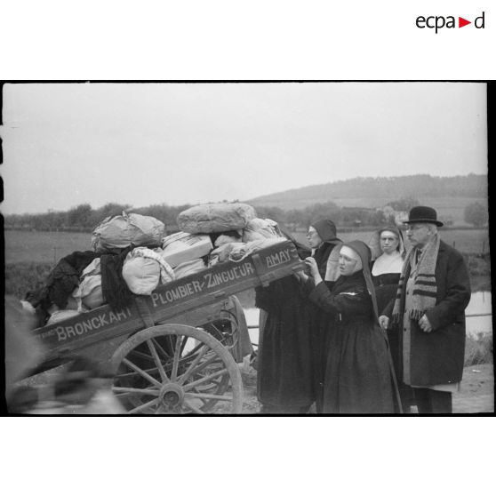 Religieuses s'attelant à pousser un chariot sur une route de Belgique.