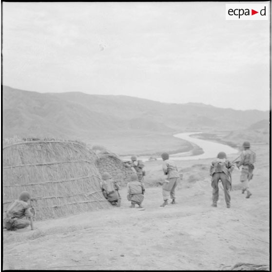 Des soldats sont postés en position de tir, autour d'une habitation.