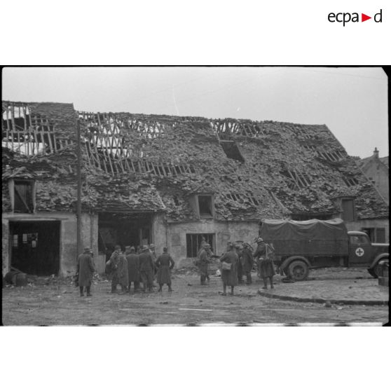 Des prisonniers français sont rassemblés devant un camion allemand.