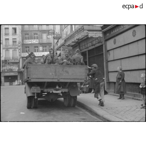 Dans une rue de Paris, un camion de la Luftwatfe chargé de soldats armés de fusil Mauser 98 k.