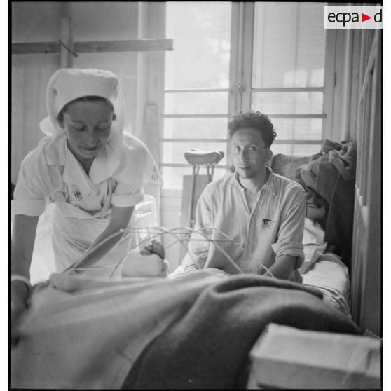 Dans le pavillon des "troupes indigènes", une infirmière donne des soins à un blessé.