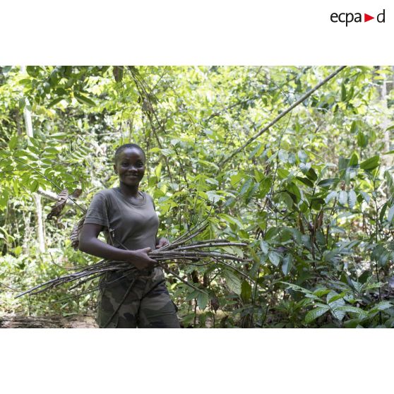 Une stagiaire du régiment du service militaire adapté (RSMA) ramasse du bois pour le feu lors d'un atelier jungle à Saint-Jean-du-Maroni, en Guyane française.