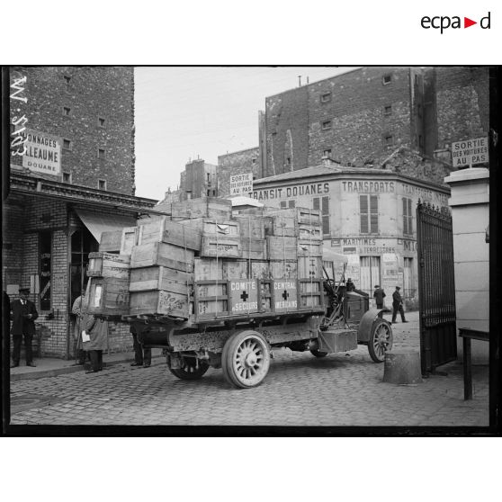 Gare des Batignolles, le hall de la gare où sont rassemblés les caisses renfermant les dons faits par les américains de l'American Relief House. L'arrivée d'un camion transportant les caisses de l'association. [légende d'origine]