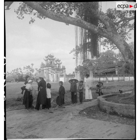 Un groupe de femmes et d'enfants vietnamiens se tient sur un chemin près de la maison communale d'Ha Hoï.