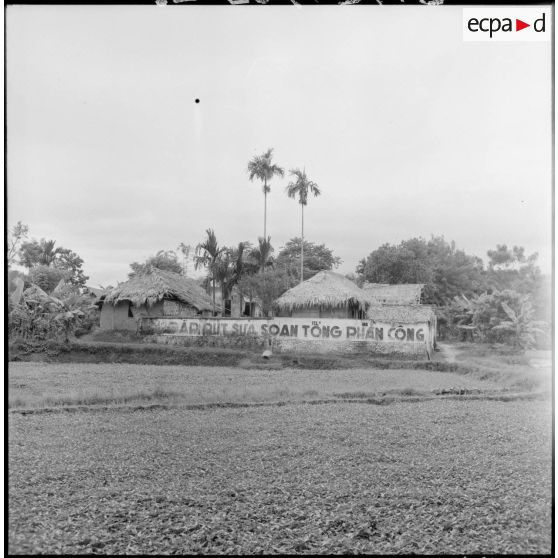 Un village dans la région de Thaï Binh qui comporte une grande banderolle sur la quelle est inscrite le message de propagande Viêt-minh : Préparons la contre-offensive générale!.