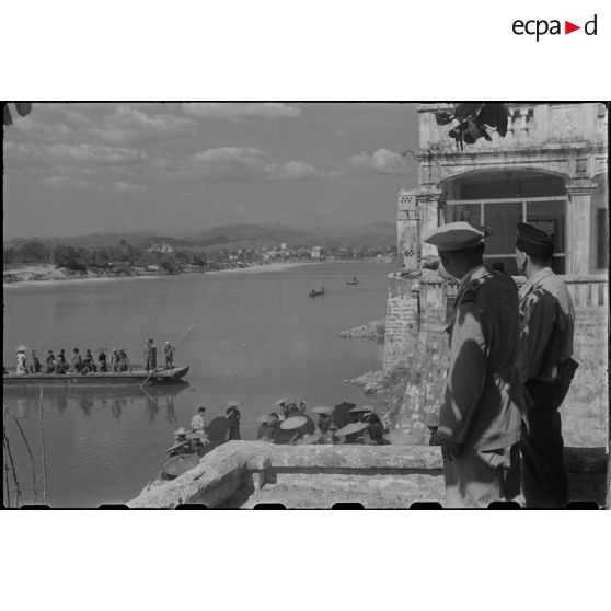 Le commandant Vong A Sang, chef de province, observe le passage d'un bac sur la rivière à Moncay (Mong Cai) en compagnie d'un militaire.