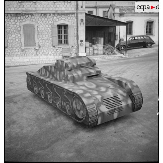 Présentation de trois quarts en plongée d'une maquette de char montée sur une Peugeot 402 dans le parc d'artillerie de Marseille.