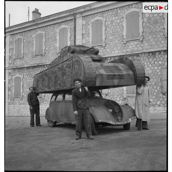 Deuxième temps de l'enlèvement d'une maquette de char montée sur une Peugeot 402, dans le parc d'artillerie de Marseille.