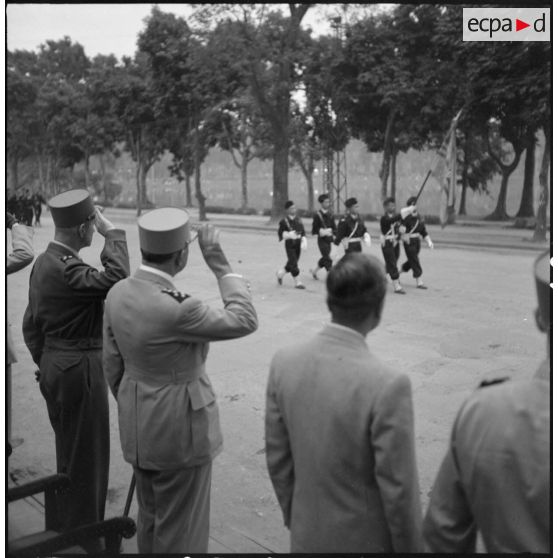 Au centre de la tribune officielle, le général de Lattre de Tassigny, commandant en chef en Indochine, salue les troupes défilant à Hanoï.