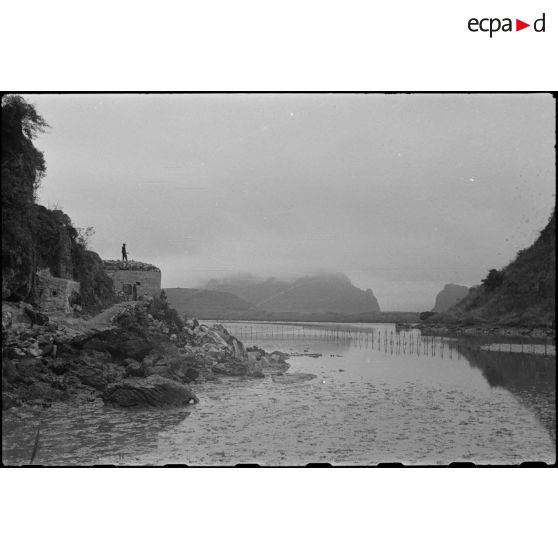Un ouvrage fortifié, construit au pied d'une falaise, en baie d'Along.