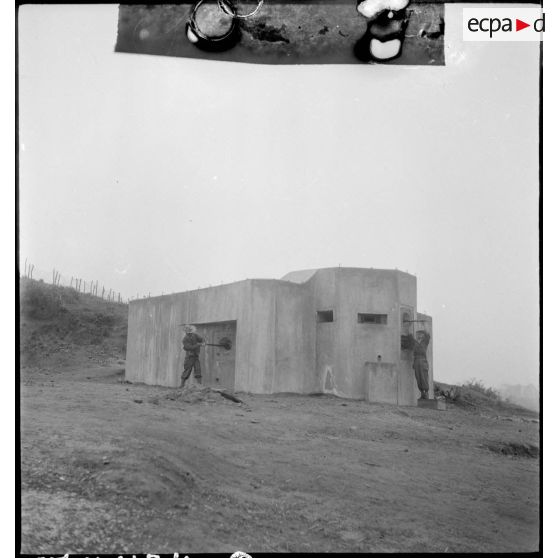 Vérification des mitrailleuses du blockhaus par deux militaires.