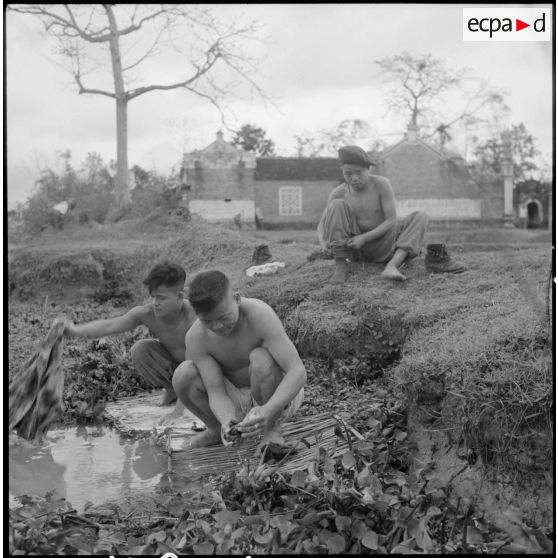 Des tirailleurs muong font leur lessive au bord de la rivière.