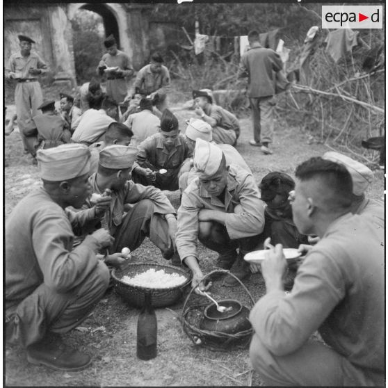 Les tirailleurs muong prennent leur repas à base de riz et de poisson séché.