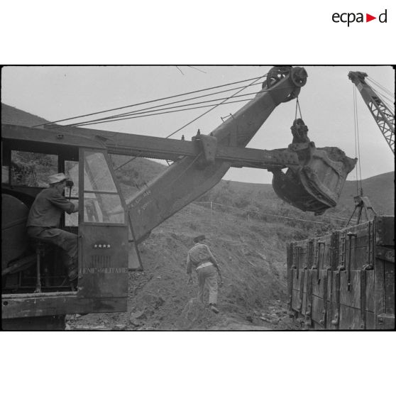 Un sapeur du génie aux commandes d'une pelle mécanique lors des travaux d'aménagement du terrain d'aviation de Kien An.