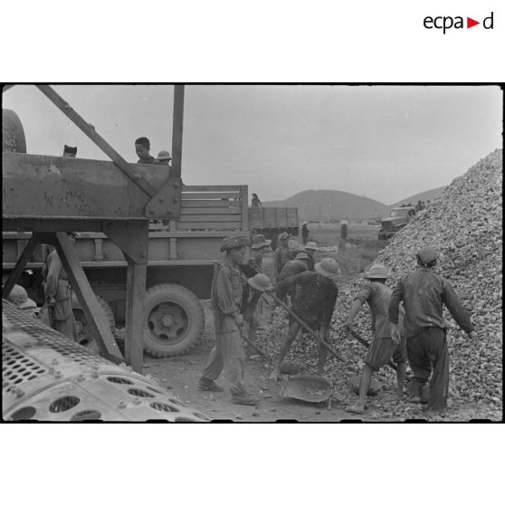 Chargement de gravats dans des camions GMC sur le chantier de construction du terrain d'aviation de Kien An.