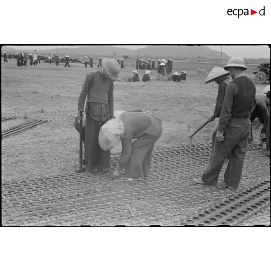 Pose de plaques en acier perforées (PSP) pour la construction de la piste d'aviation de Kien An par des travailleurs tonkinois.