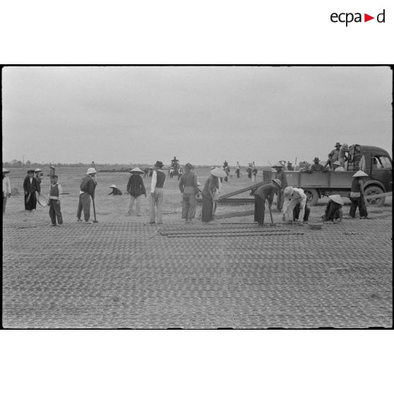 Pose de plaques en acier perforées (PSP) pour la construction de la piste d'aviation de Kien An par des travailleurs tonkinois.