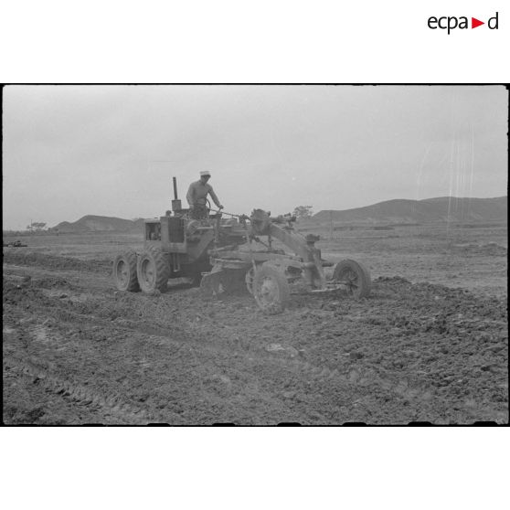 Un sapeur du génie aplanit le terrain avec une niveleuse lors des travaux de construction du terrain d'aviation de Kien An.