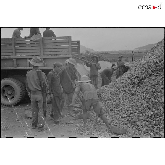 Des travailleurs tonkinois chargent des gravats à bord d'un camion GMC au cours des travaux d'aménagement du terrain d'aviation à Kien An.
