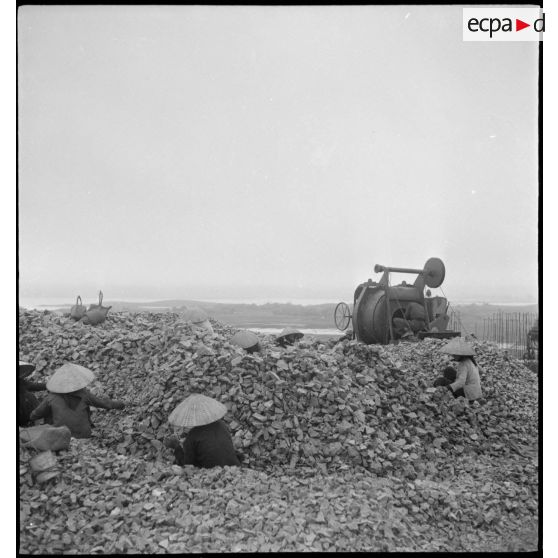 Des travailleurs tonkinois cassent des cailloux lors des travaux d'aménagement du terrain d'aviation de Kien An.